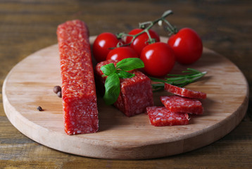 Tasty salami sausage and spices on wooden background