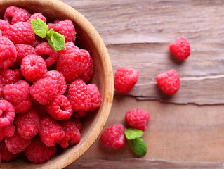 Ripe sweet raspberries in bowl on table close-up