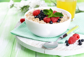 Tasty oatmeal with berries on table close-up