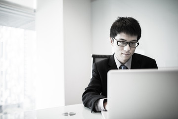 Young handsome man using laptop in his office