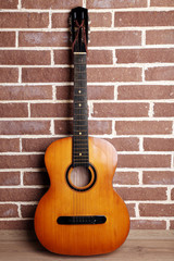 Fototapeta na wymiar Guitar on the floor on brick wall background