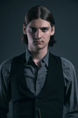 Western 1900 fashion man with brown hair. Studio shot against gr