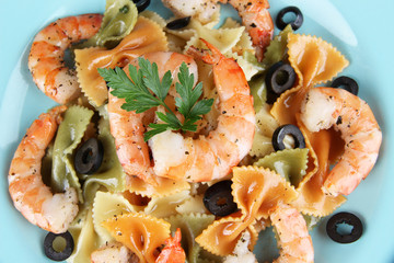 Fresh prawns with coloured macaroni and olives in a blue plate
