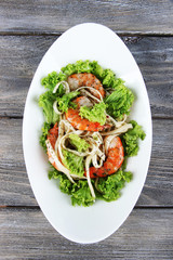 Fresh prawns with spaghetti, olives and lettuce in a white oval