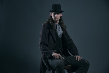 Fototapeta premium Western 1900 fashion man with brown hair and hat sitting on chai