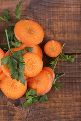 Slices of carrot and parsley on wooden background