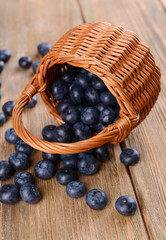 Delicious blueberries in wicker basket on table close-up