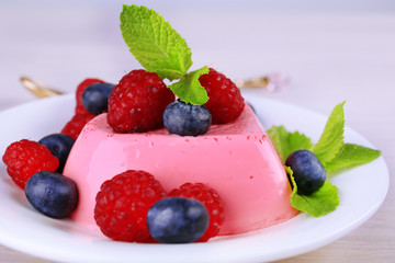 Heart shaped cake with berries on plate on wooden background