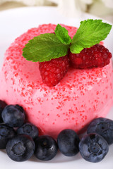 Round shaped cake with berries on plate on wooden background