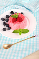Round shaped cake with berries on plate on napkin