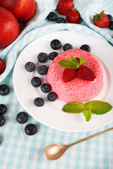 Round shaped cake with berries on plate on table cloth