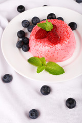 Round shaped cake with berries on plate on table cloth
