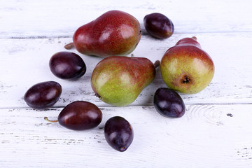 Beautiful ripe pears and plums on wooden table close-up