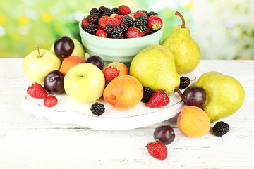 Ripe fruits and berries on table on bright background