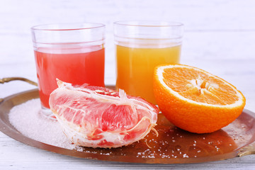 Different sliced citrus fruits and glasses of juice