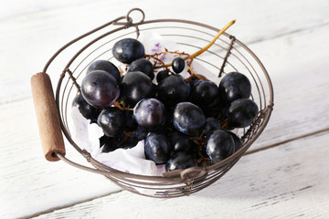 Purple grapes in basket on wooden background