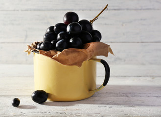 Purple grape in cup on wooden background