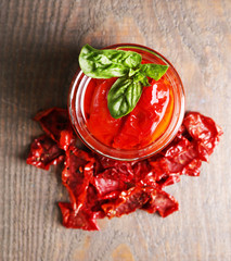Sun dried tomatoes in glass jar, basil leaves