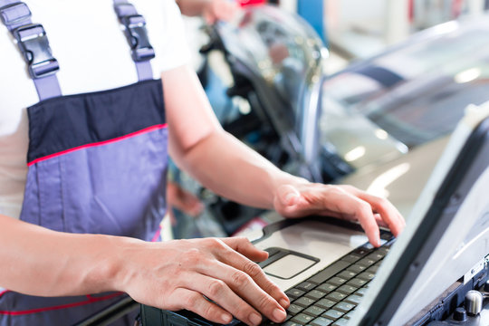 Car mechanic with diagnosis tool in auto workshop