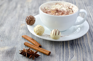 Pralines and a cup of cappuccino copy space wooden background
