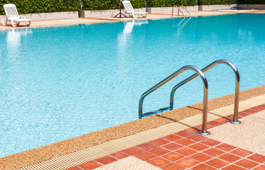 A view of a light clear blue swimming pool with steel ladder