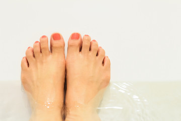 Bath time. Woman feet in the water tub.