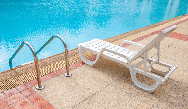 Relaxing beach chair beside grab bars ladder and blue swimming p
