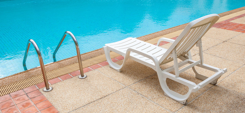 White lounge chair at the pool side near ladder; blue swimming p