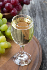 glass of white wine and grapes on a wooden board, top view