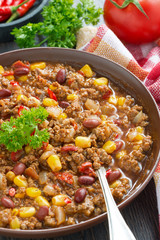 spicy Mexican dish chili con carne in a brown pottery plate