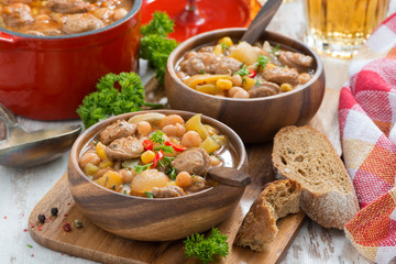 vegetable stew with sausages in a wooden bowl on board and bread