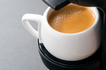 white cup of coffee in the coffee machine, close-up