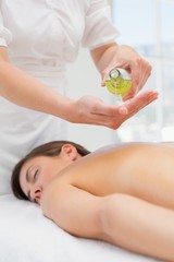 Obraz na płótnie Canvas Woman getting massage oil on her back at spa center