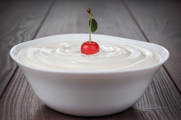white bowl full of sour cream with cherry