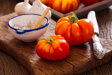 Fleischtomaten mit Messer und Salz auf Schneidebrett