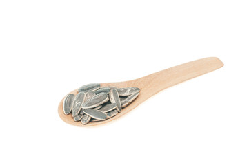 Sunflower seeds on wooden spoon isolated with white background.