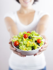 Young woman & vegetable salad isolated in white