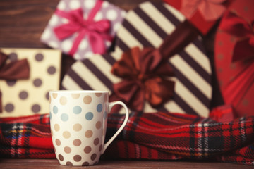 Winter tea in a cup and christmas gifts on background.
