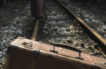 Woman and vintage suitcase on railway road