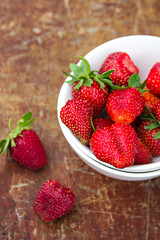  strawberries in a bowl and scattered on the old table