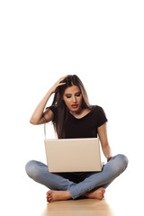 startled girl sitting on the floor and working on laptop