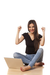 happy girl with the winning gesture working on laptop