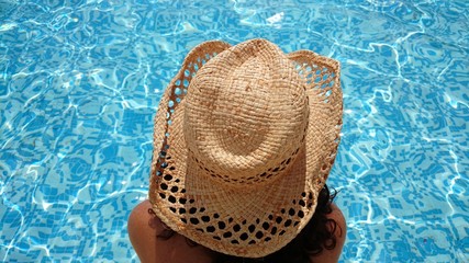 Mujer con sombrero observando piscina