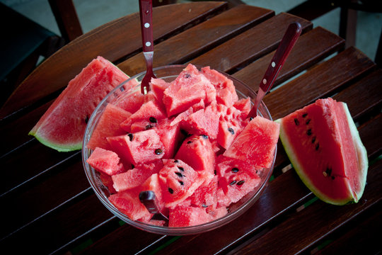 Watermelon picies in transparent bowl on wooden table