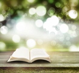 Open book on table and blurred green background