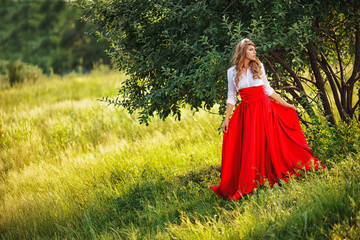 woman in red skirt standing under the tree