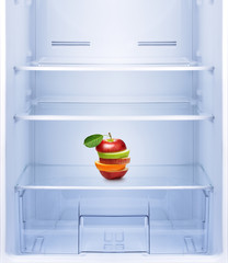 Apples and orange fruit in empty refrigerator.