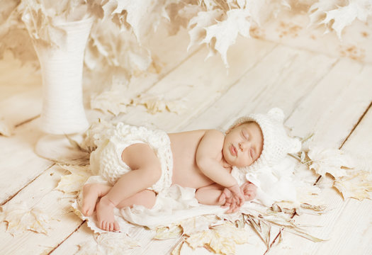 Newborn baby sleeping on leaves over white wooden background. Fi