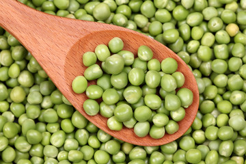 Fresh green peas in a wooden spoon