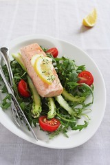 Portion steam salmon with a salad of arugula and fresh asparagus